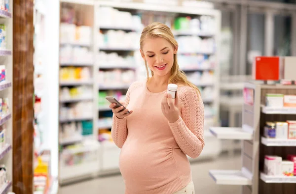 Glad gravid kvinna med läkemedel på apotek Royaltyfria Stockbilder