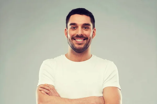 Lächelnder Mann mit verschränkten Armen vor grauem Hintergrund — Stockfoto