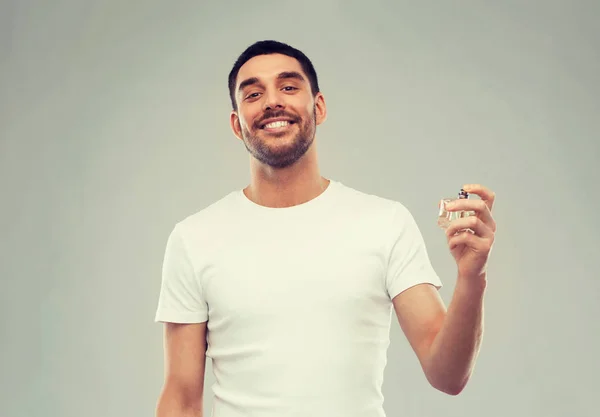 Uomo sorridente con profumo maschile su sfondo grigio — Foto Stock