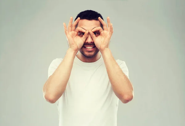 Mann bastelt Fingerbrille vor grauem Hintergrund — Stockfoto