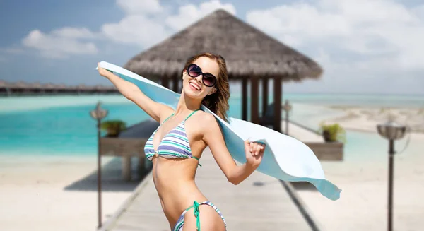 Vrouw in bikini en zonnebril met handdoek op strand — Stockfoto