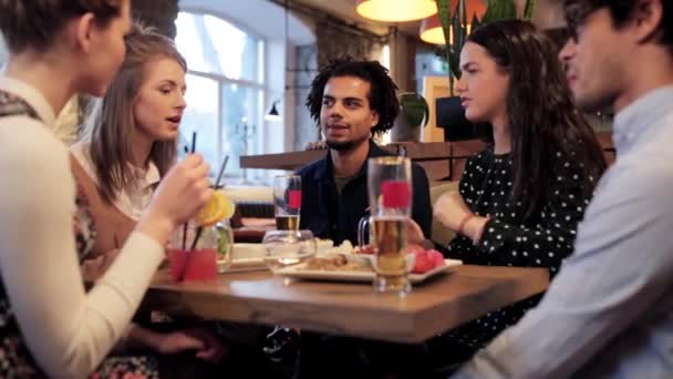 Счастливые друзья едят и пьют в баре или кафе — стоковое видео