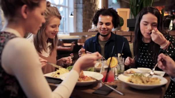 Счастливые друзья едят и пьют в ресторане — стоковое видео