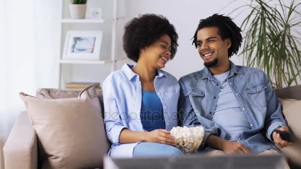 Улыбающаяся пара с попкорном смотрит телевизор дома — стоковое видео