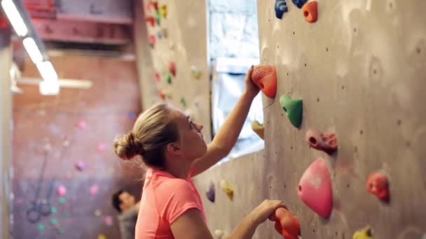 Jovem mulher exercitando na parede do ginásio de escalada interior — Vídeo de Stock