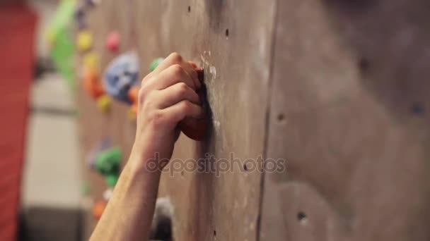 Νεαρός άνδρας γυμνάζεται σε εσωτερικούς τοίχους αναρρίχησης γυμναστήριο — Αρχείο Βίντεο