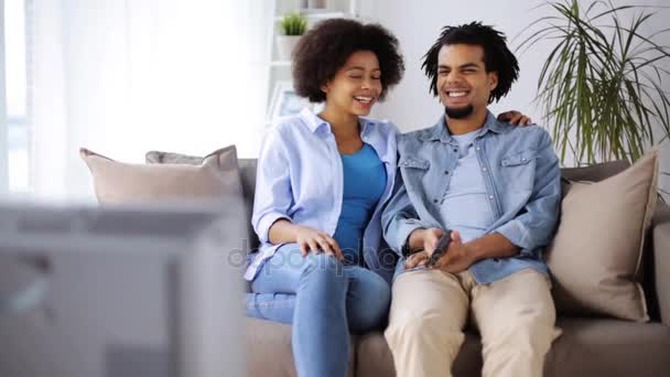 Счастливая улыбающаяся пара смотрит телевизор дома — стоковое видео