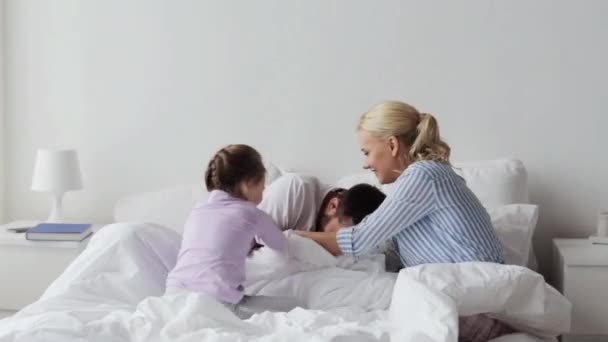 Счастливая семья, весело проводящая время в постели дома — стоковое видео