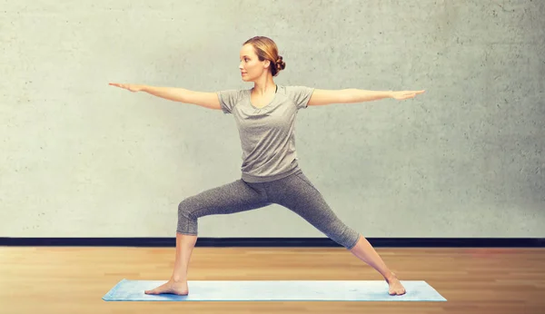 Kvinnan gör krigare yogaställning på matta — Stockfoto