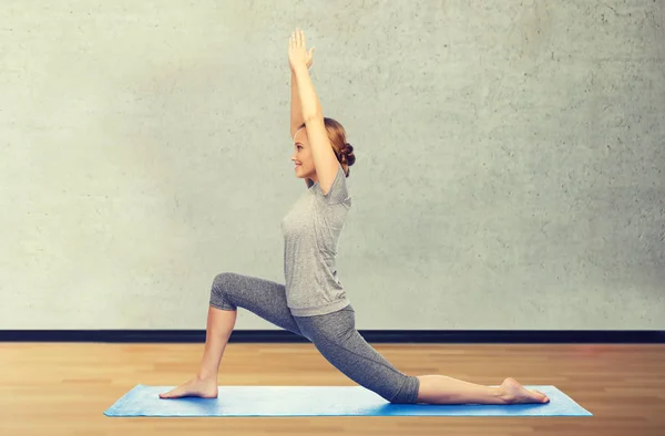 Glückliche Frau macht Yoga in niedrigem Ausfallschritt auf Matte — Stockfoto
