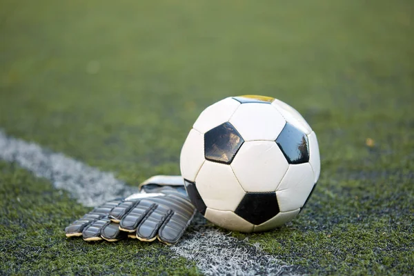 Футбольный мяч и вратарские перчатки на поле — стоковое фото