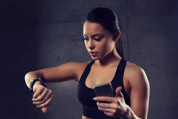 Mulher com relógio de frequência cardíaca e smartphone no ginásio — Fotografia de Stock