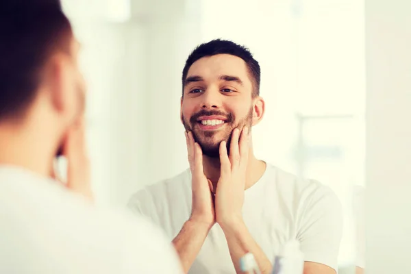 Heureux jeune homme qui cherche à miroir à la maison salle de bain — Photo