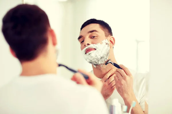 Man shaving beard with razor blade at bathroom — Stock Photo, Image
