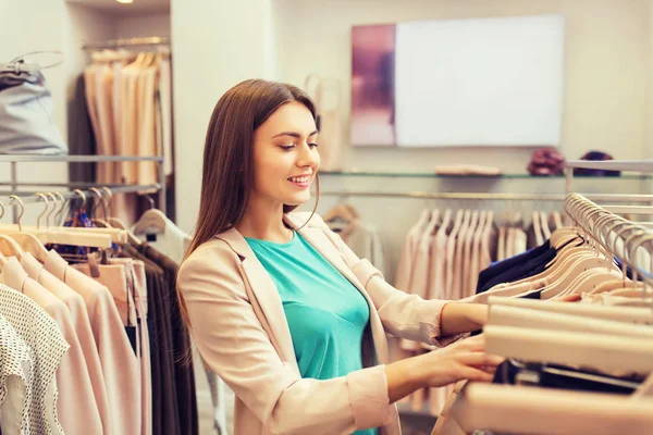 Gelukkig jonge vrouw kleding in winkelcentrum kiezen — Stockfoto