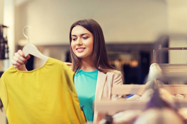 Щаслива молода жінка вибирає одяг у торговому центрі — стокове фото