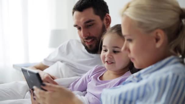 Ευτυχισμένη οικογένεια με tablet pc στο κρεβάτι στο σπίτι — Αρχείο Βίντεο