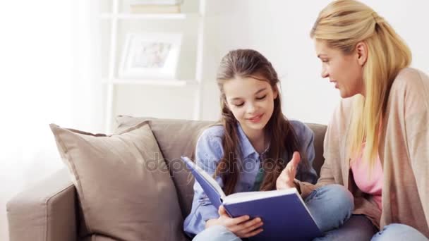 Счастливая девочка с мамой, читающей книгу дома — стоковое видео