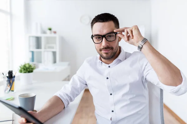 Homem de negócios em óculos com tablet pc no escritório — Fotografia de Stock
