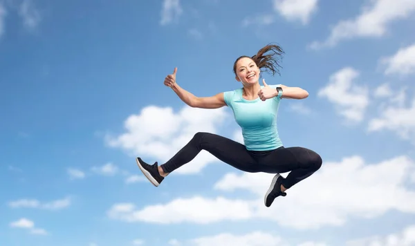 Gelukkig sportieve jonge vrouw springen in de blauwe hemel — Stockfoto