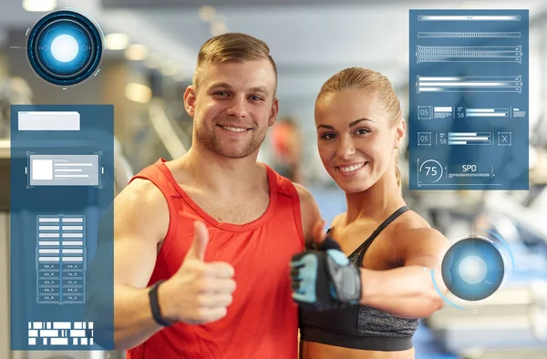 Sonriente hombre y mujer mostrando pulgares hacia arriba en el gimnasio —  Fotos de Stock