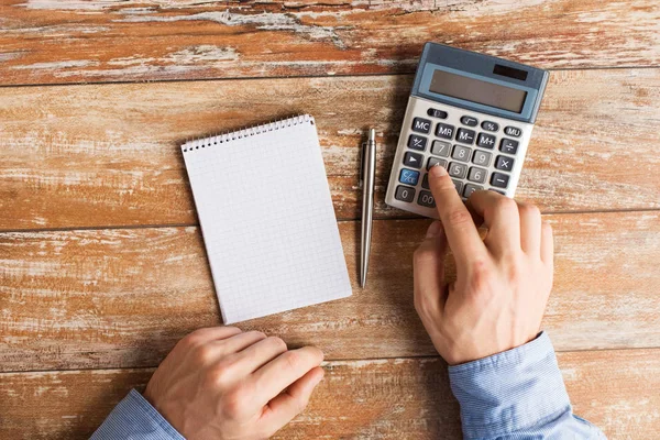 Close up of hands with calculator and notebook — Stock Photo, Image