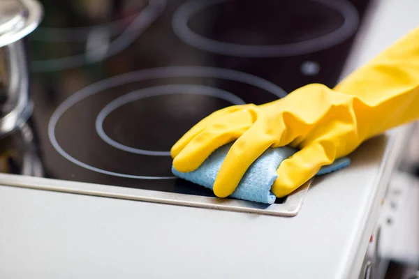 Tangan dengan kain pembersih kompor di dapur rumah — Stok Foto