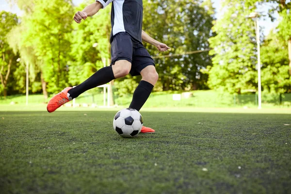 Футболист играет с мячом на поле — стоковое фото