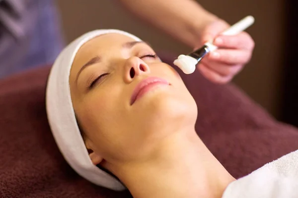 Esteticista aplicando máscara facial para a mulher no spa — Fotografia de Stock