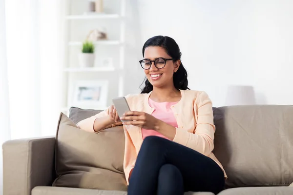 Szczęśliwa kobieta wiadomość SMS-y na smartfonie w domu — Zdjęcie stockowe