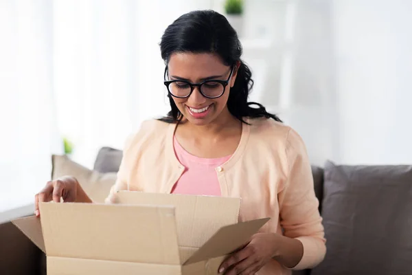 Счастливая молодая индийская женщина с коробкой для посылок дома — стоковое фото