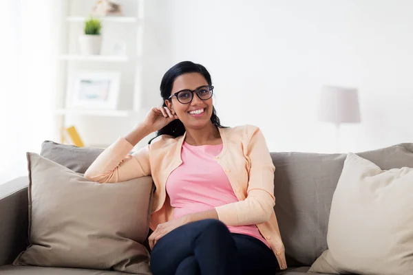 Lyckligt leende ung kvinna sitter på soffan hemma — Stockfoto