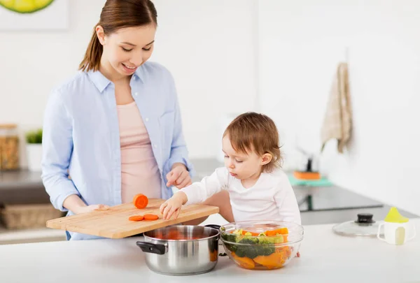 Mãe feliz e bebê cozinhar comida em casa cozinha — Fotografia de Stock