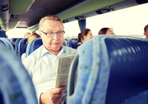 Happy senior man reading newspaper in travel bus — Stock Photo, Image