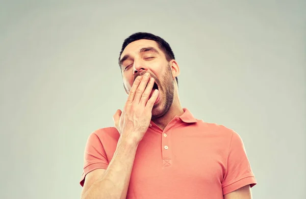 Sbadigliare l'uomo su sfondo grigio — Foto Stock