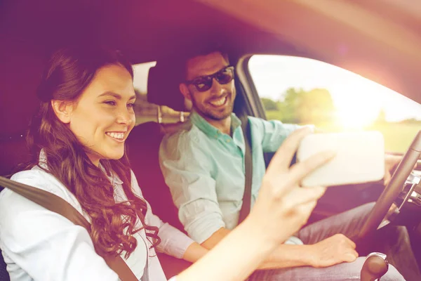 Feliz pareja en coche tomando selfie con smartphone —  Fotos de Stock