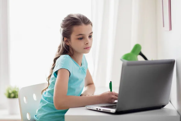 Mädchen mit Laptop schreibt zu Hause an Notizbuch — Stockfoto