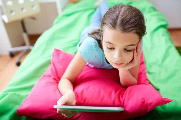 Chica sonriente con tableta PC acostado en la cama en casa —  Fotos de Stock