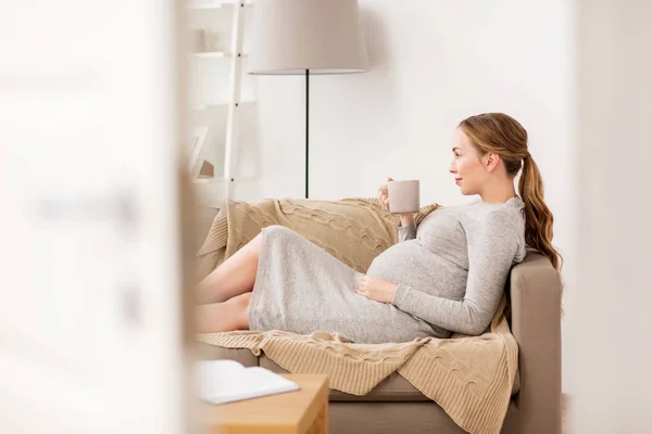 Щаслива вагітна жінка з чашкою п'є чай вдома — стокове фото