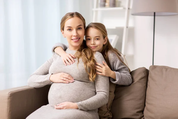 Szczęśliwy w ciąży kobieta i dziewczynka przytulanie w domu — Zdjęcie stockowe