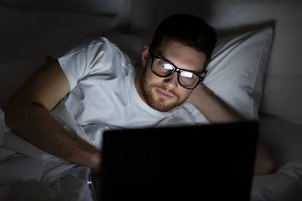 Jonge man met laptop in bed thuis slaapkamer — Stockfoto