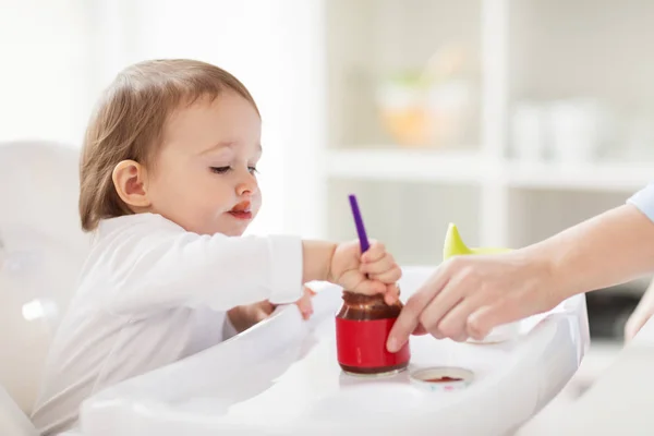 Baby mit Löffel isst Püree aus Glas zu Hause — Stockfoto