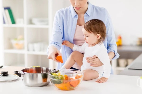 Mère heureuse et bébé cuisine légumes à la maison — Photo
