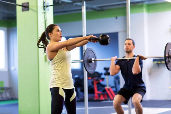 Мужчина и женщина с гирями упражнения в тренажерном зале — стоковое фото