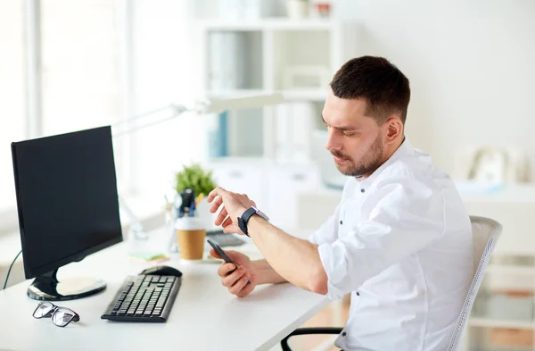 Homme d'affaires avec smartphone et ordinateur au bureau — Photo