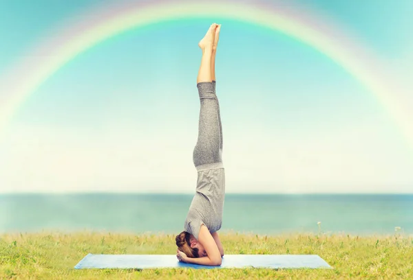 Mulher fazendo ioga na pose headstand no tapete — Fotografia de Stock