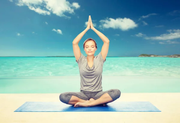 Mujer haciendo meditación de yoga en pose de loto en la estera — Foto de Stock