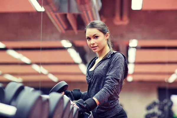 Mujer joven eligiendo mancuernas en el gimnasio —  Fotos de Stock