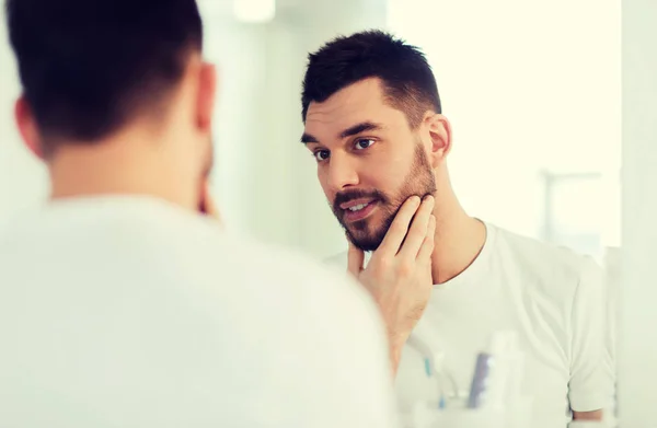 Щасливий молодий чоловік дивиться дзеркало в домашній ванній — стокове фото