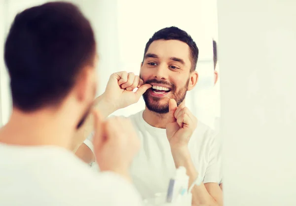 Hombre con hilo dental limpieza de dientes en el baño —  Fotos de Stock